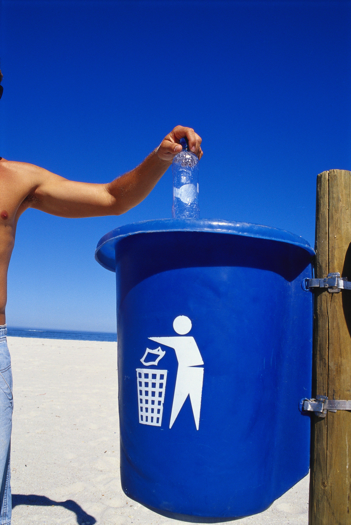 Eine Person wirft eine Flasche in den Müll. Thema Verpackungsrecycling